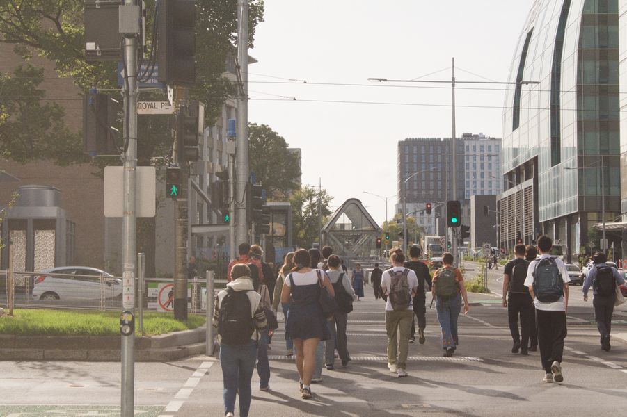Passengers walking across Royal Parade, facing the University of Melbourne.